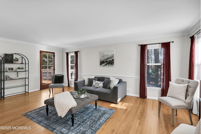 living area featuring ornamental molding, light wood-style flooring, and baseboards