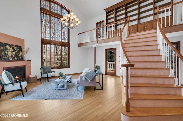 living area featuring stairway, a glass covered fireplace, a wealth of natural light, and wood finished floors