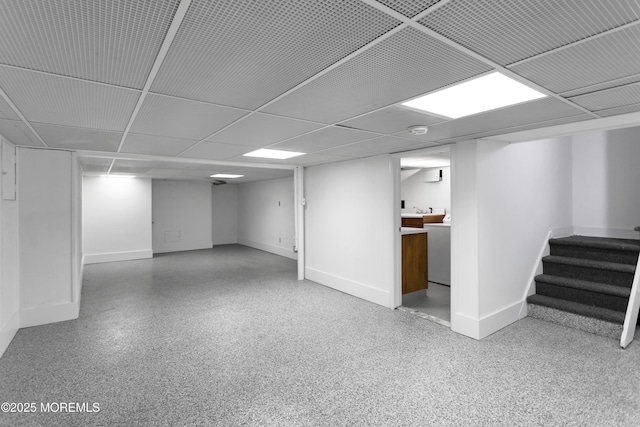 finished basement featuring baseboards, stairway, and a drop ceiling