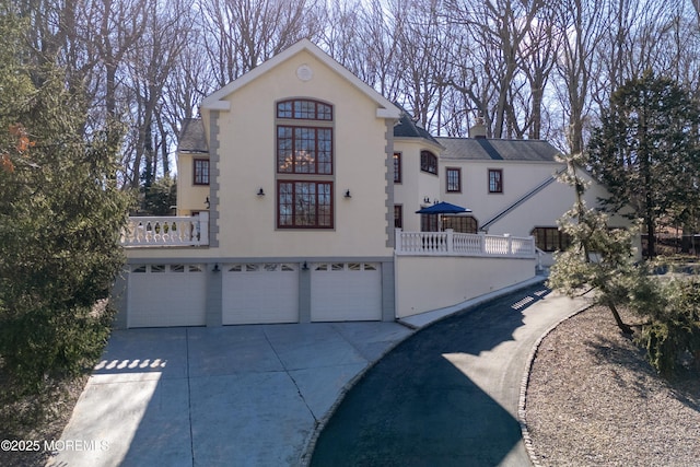 view of front of home featuring a garage, a chimney, concrete driveway, and stucco siding