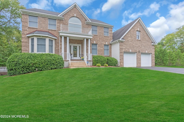 view of front of house featuring a balcony, a front lawn, and a garage