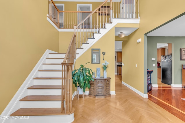 stairs featuring parquet flooring and a towering ceiling