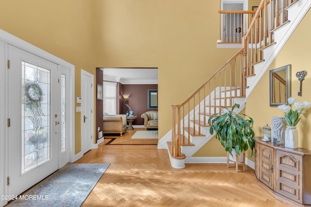 foyer entrance featuring a high ceiling, light parquet flooring, and crown molding