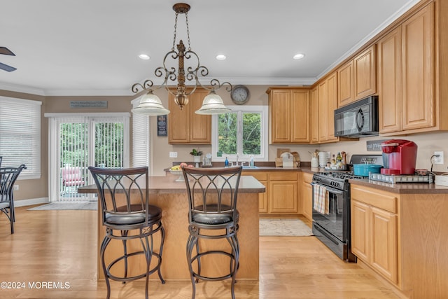 kitchen featuring crown molding, light wood-type flooring, black appliances, and pendant lighting