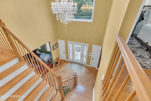 foyer entrance with a high ceiling, a chandelier, and parquet floors