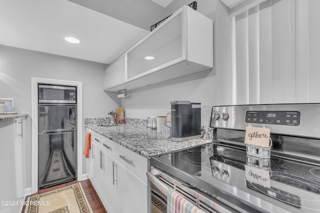 kitchen with light stone counters, white cabinets, appliances with stainless steel finishes, and wood-type flooring