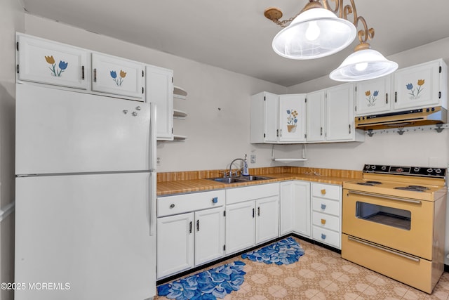 kitchen featuring white fridge, decorative light fixtures, white cabinetry, range with electric cooktop, and sink