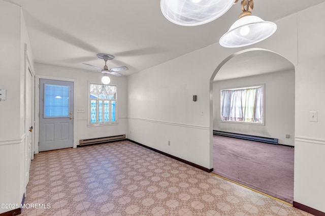 interior space with a wealth of natural light, baseboard heating, and ceiling fan