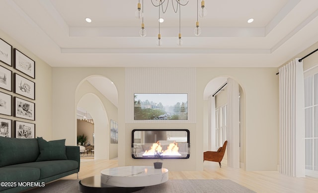 living room featuring a multi sided fireplace, a raised ceiling, and hardwood / wood-style flooring