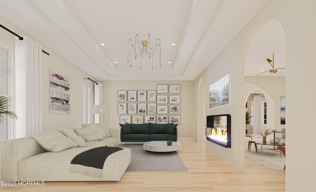 living room with a raised ceiling, light hardwood / wood-style floors, and a notable chandelier