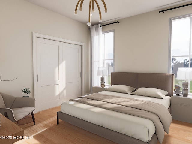 bedroom with a chandelier, light wood-type flooring, and a closet