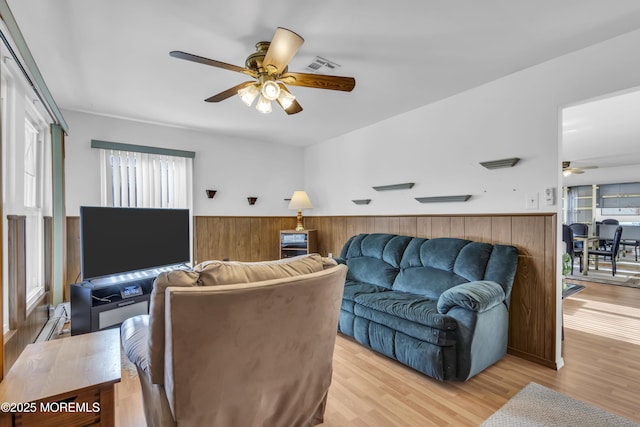 living room with light wood-type flooring, wooden walls, and ceiling fan