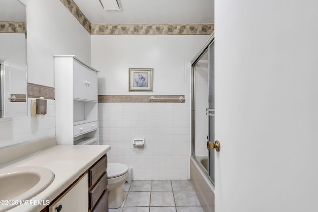 full bathroom featuring tile patterned flooring, tile walls, combined bath / shower with glass door, toilet, and vanity