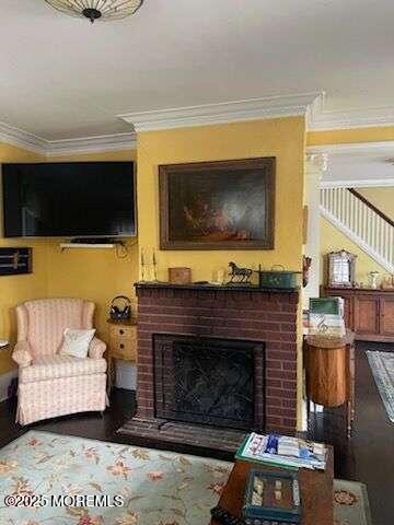 living area with a brick fireplace and crown molding