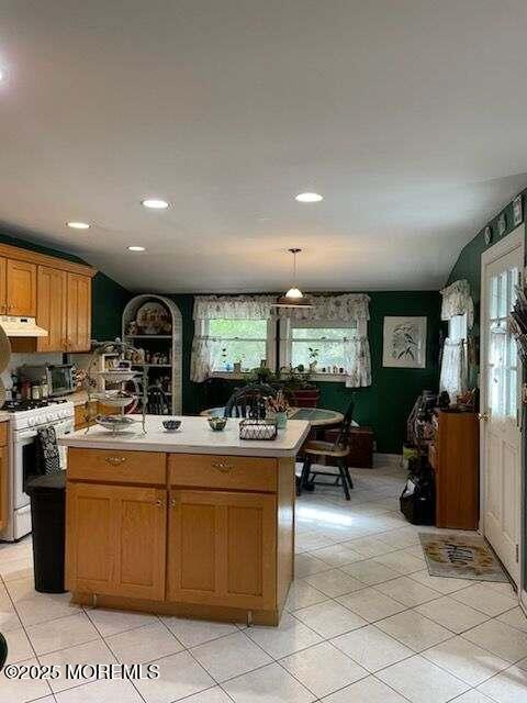 kitchen with decorative light fixtures, white gas range oven, and a center island