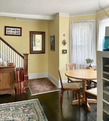 dining space featuring ornamental molding and dark wood-type flooring