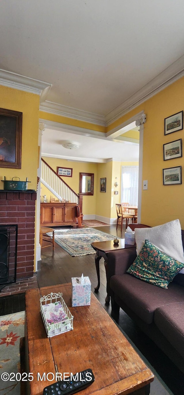 living room with a brick fireplace, ornamental molding, and dark hardwood / wood-style floors