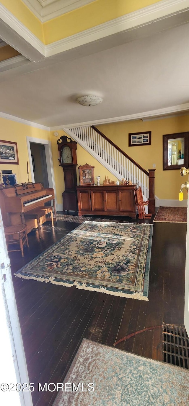 stairway with ornamental molding and hardwood / wood-style floors