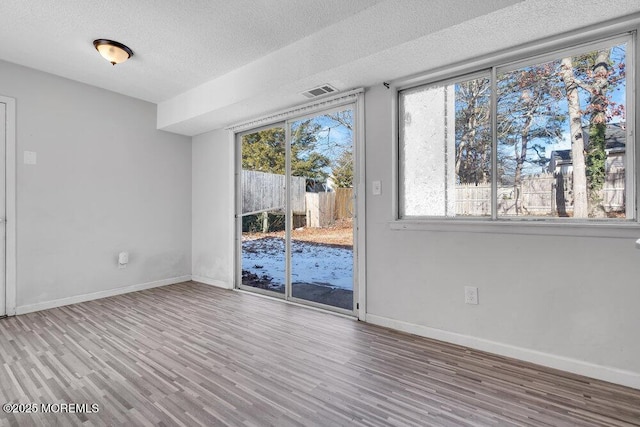 unfurnished room featuring a textured ceiling and light hardwood / wood-style flooring