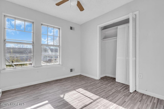 unfurnished bedroom featuring a closet, ceiling fan, a textured ceiling, and light wood-type flooring