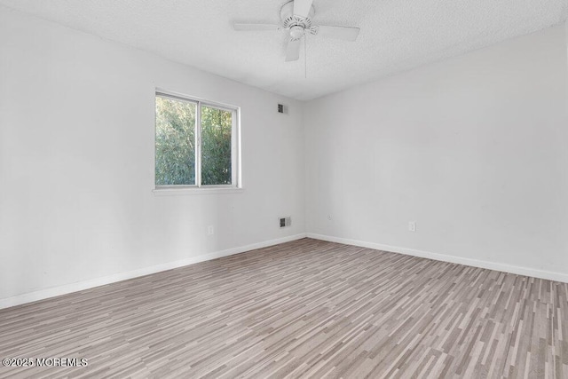 spare room with a textured ceiling, light wood-type flooring, and ceiling fan