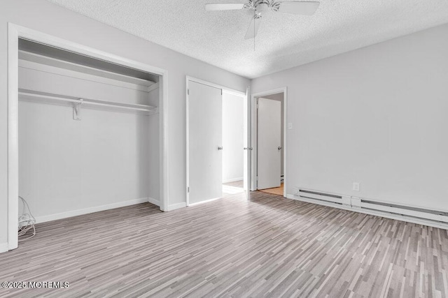 unfurnished bedroom featuring a closet, a baseboard heating unit, ceiling fan, and light hardwood / wood-style flooring