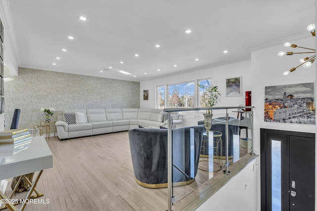 living room with light hardwood / wood-style floors, an inviting chandelier, and crown molding