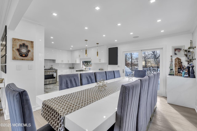 dining space with light wood-type flooring and ornamental molding