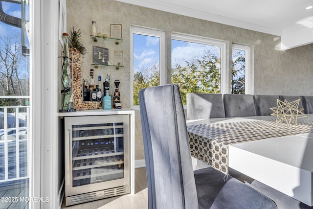 dining area featuring indoor bar, wine cooler, and ornamental molding