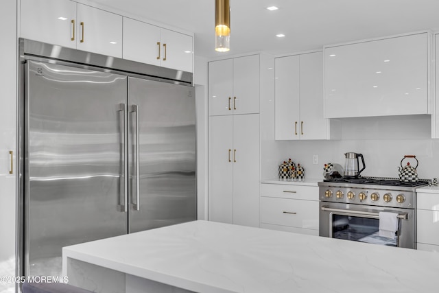 kitchen with white cabinets, light stone counters, hanging light fixtures, and high quality appliances