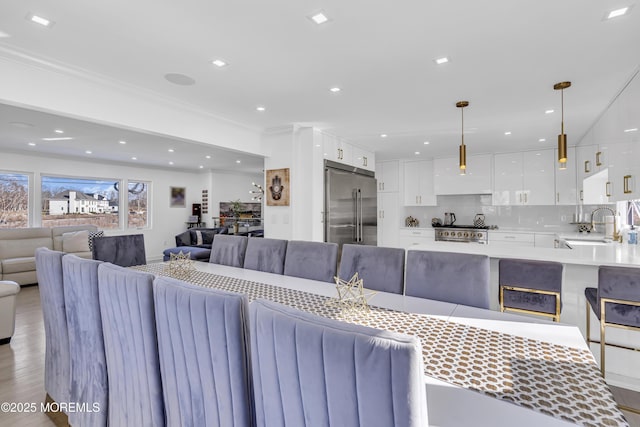 living room featuring light hardwood / wood-style floors, ornamental molding, and sink