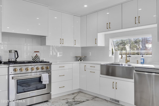 kitchen with white cabinets, appliances with stainless steel finishes, tasteful backsplash, and sink