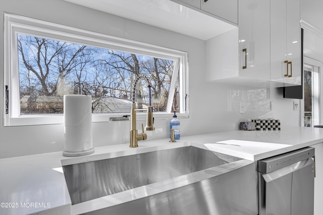 room details with decorative backsplash, sink, white cabinets, and stainless steel dishwasher