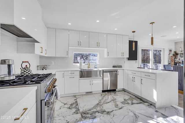 kitchen featuring sink, stainless steel appliances, kitchen peninsula, pendant lighting, and white cabinets