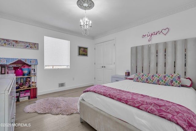 bedroom featuring a notable chandelier, light hardwood / wood-style floors, ornamental molding, and a closet