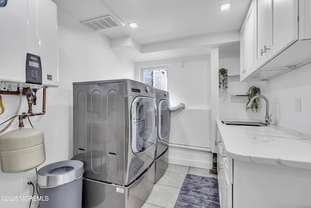 washroom featuring cabinets, washer and clothes dryer, water heater, sink, and light tile patterned floors