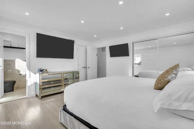 bedroom featuring ensuite bath, ornamental molding, and light wood-type flooring