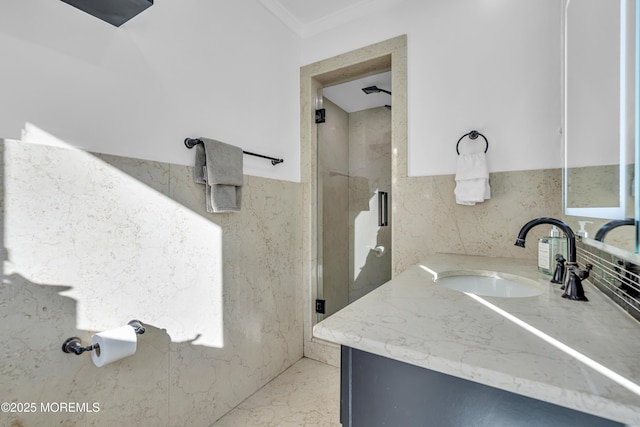 bathroom featuring vanity, a shower with shower door, ornamental molding, and tile walls