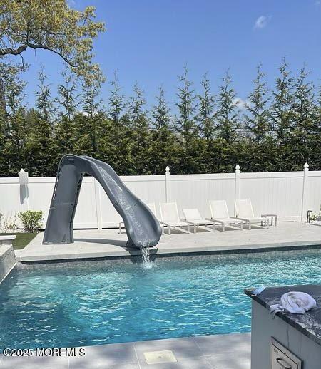 view of swimming pool featuring a patio, pool water feature, and a water slide