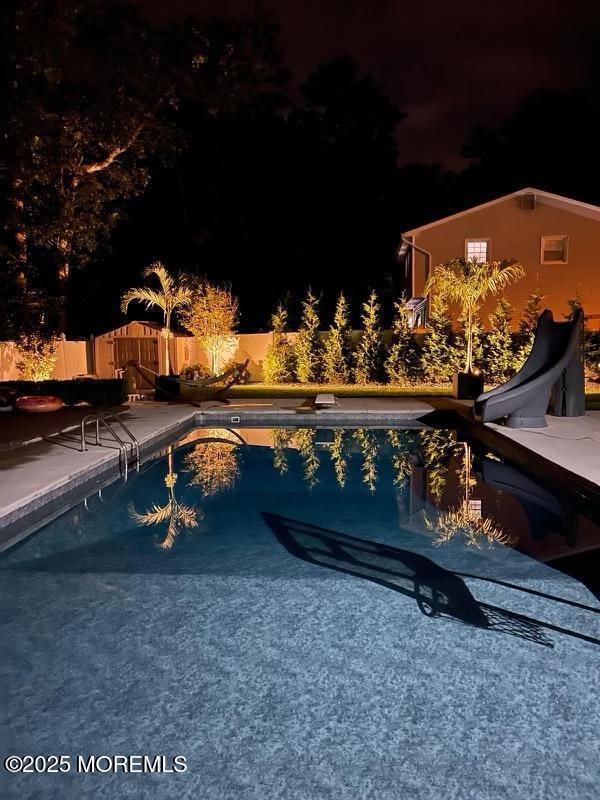 view of swimming pool featuring a diving board, a patio, and a water slide