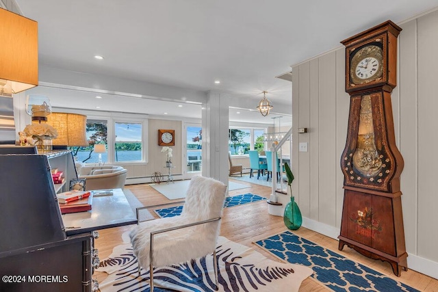 living room featuring baseboard heating, a notable chandelier, and light hardwood / wood-style flooring