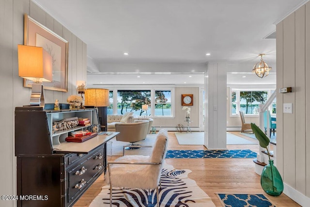 interior space with light wood-type flooring, an inviting chandelier, wooden walls, and a baseboard heating unit