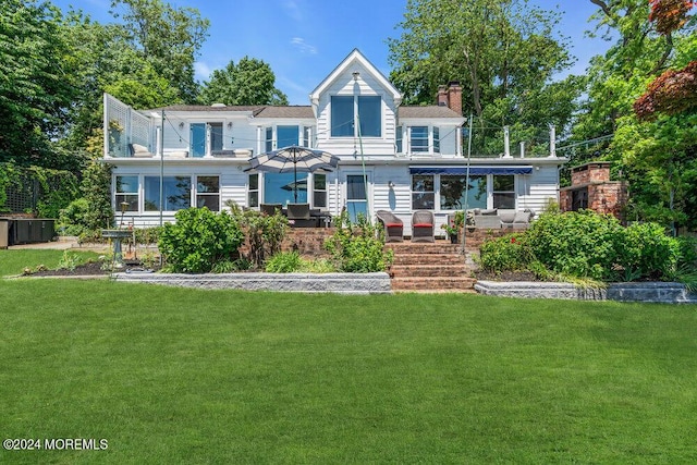 view of front of home with a sunroom and a front lawn