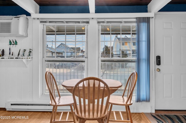 dining space featuring a wall mounted air conditioner and hardwood / wood-style flooring