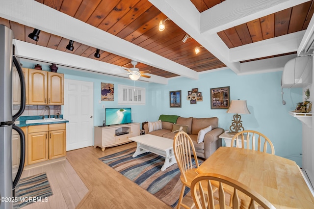 living room featuring beamed ceiling, light wood-type flooring, ceiling fan, wooden ceiling, and sink