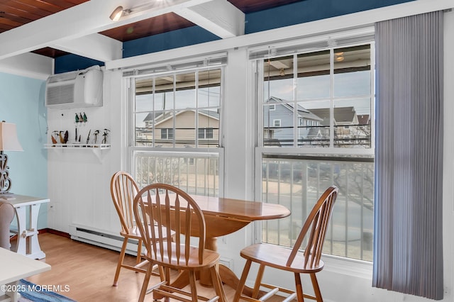 dining area with a baseboard heating unit, a wall mounted AC, and hardwood / wood-style floors