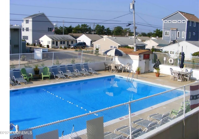 community pool featuring a patio area, a residential view, and fence