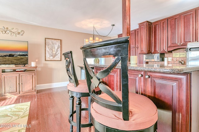 kitchen featuring tasteful backsplash, a notable chandelier, and light wood-type flooring