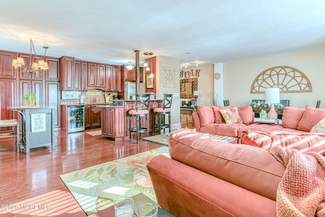 living room featuring wine cooler, hardwood / wood-style floors, and a chandelier