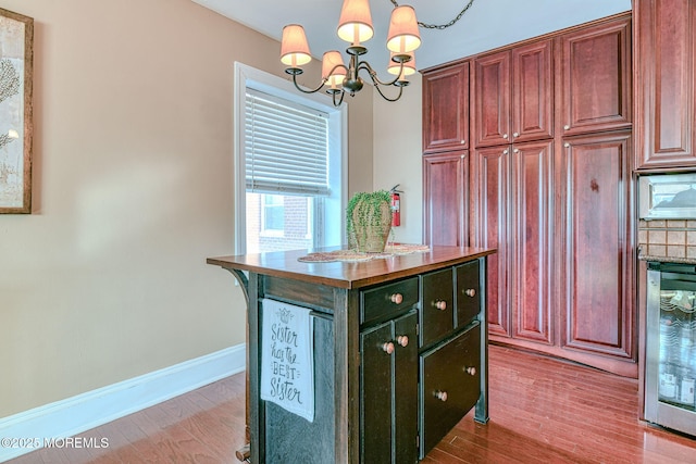 kitchen featuring pendant lighting, a center island, wine cooler, wood-type flooring, and a chandelier